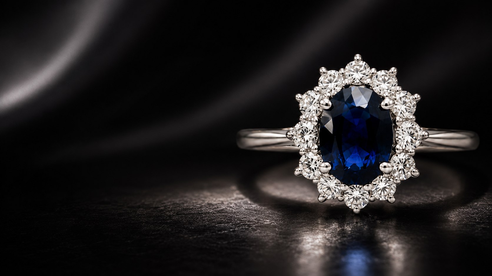 Anel de safira azul oval em halo de brilhantes, ouro branco, sobre fundo escuro dramático — peça St. Martin